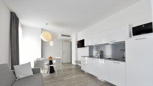 A modern kitchen with white cabinets, a built-in oven, and a flat-screen TV.
