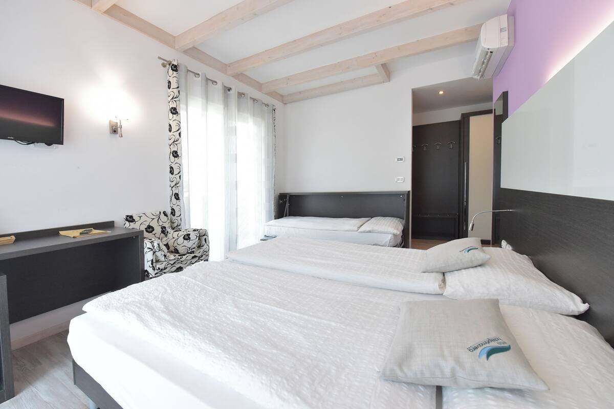 Ein modernes Hotelzimmer mit zwei Betten, einem Schreibtisch und einem Fernseher.