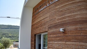 A wooden exterior wall with a sign reading "Primavera Apartments & Suites."