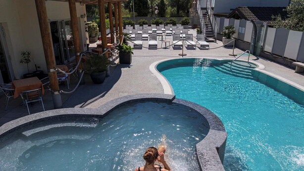 A swimming pool with a heart-shaped section, lounge chairs, and a covered seating area.