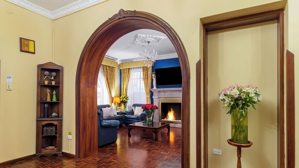 A living room with a fireplace, a blue sofa, and a wooden coffee table. - La Cartuja (Quito)