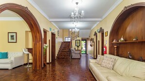 A spacious hallway with a wooden floor, a staircase, a white sofa, and a chandelier. - La Cartuja (Quito)