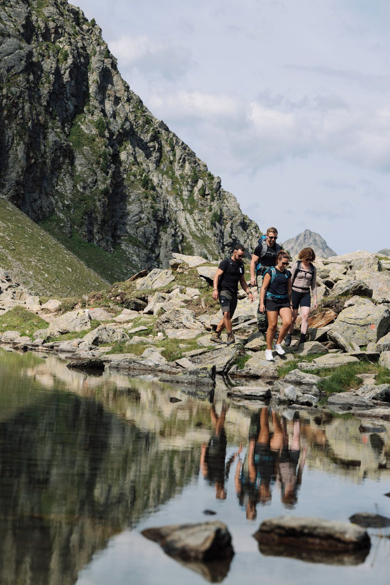 A group of hikers on a rocky terrain with a body of water in the foreground.