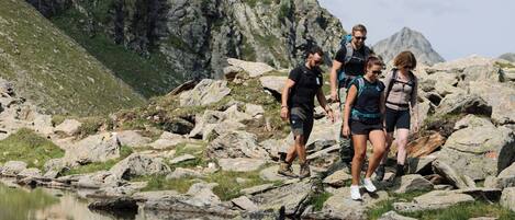 A group of hikers on a rocky terrain with a body of water in the foreground.