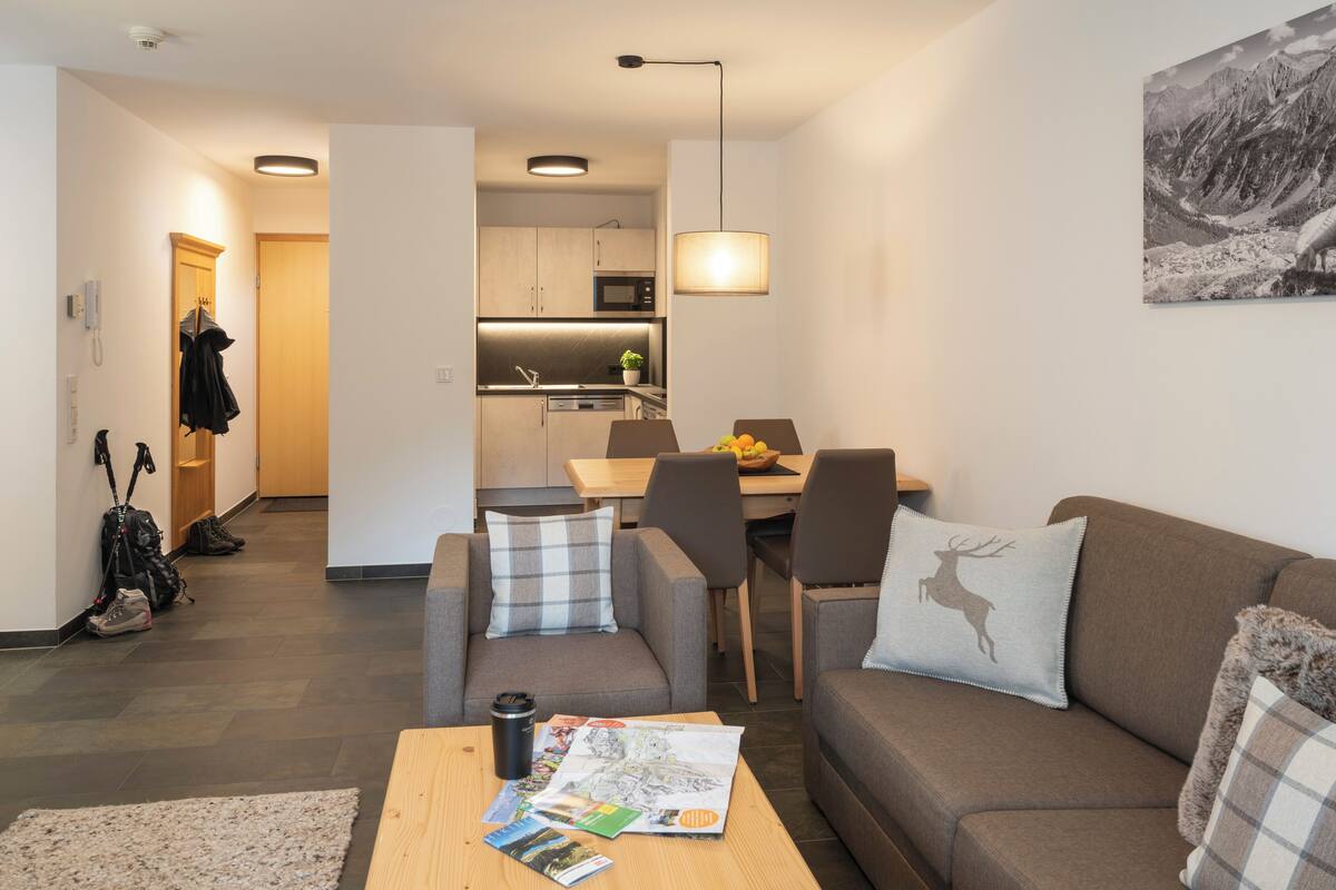 Una sala de estar moderna con sofá, mesa de centro y comedor con mesa y sillas.