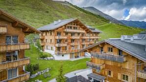 A chalet-style hotel with multiple balconies, a ski lift, and a mountain backdrop. - AlpinLodges Kühtai (Silz)