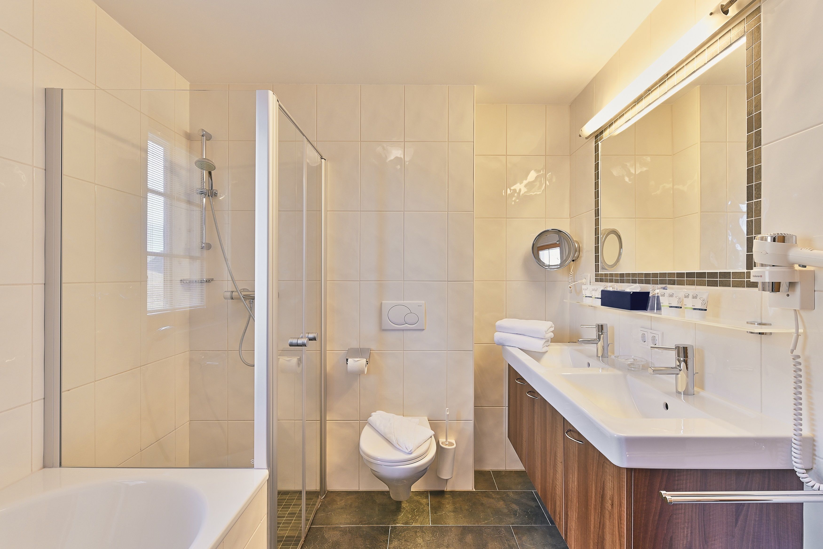 A modern bathroom with a glass-enclosed shower, a toilet, and a vanity with a mirror.