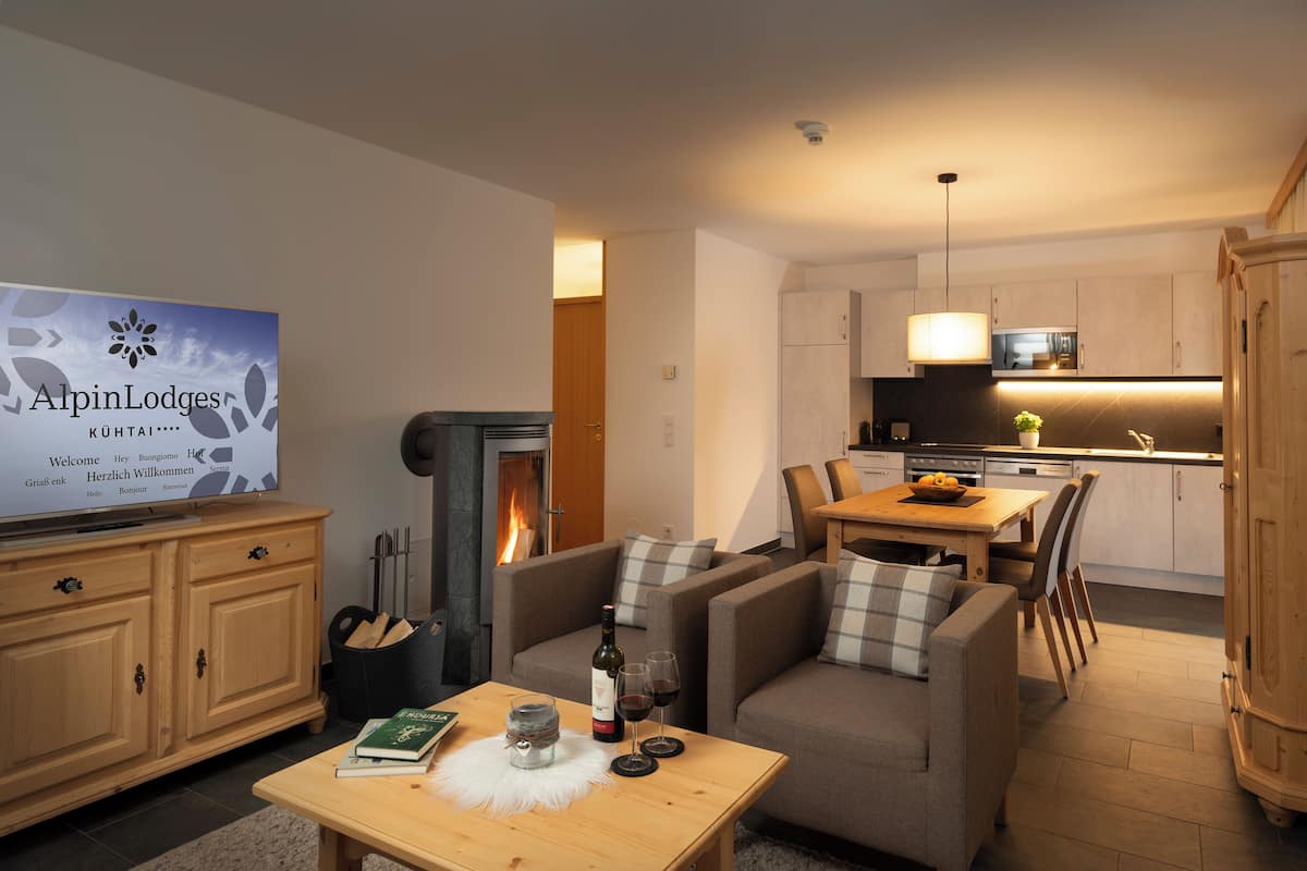 Una sala moderna con chimenea, un comedor y una cocina. Hay un televisor en la pared y un mueble de madera.