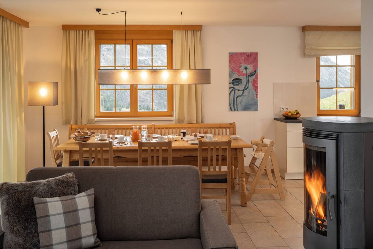 Una sala de estar acogedora con chimenea, un comedor con mobiliario de madera y un amplio ventanal con cortinas.