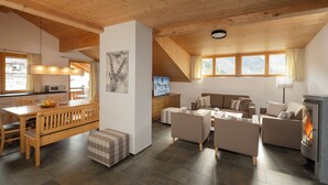 A spacious living area with a wooden dining table, sofas, and a fireplace. - AlpinLodges Kühtai (Silz)