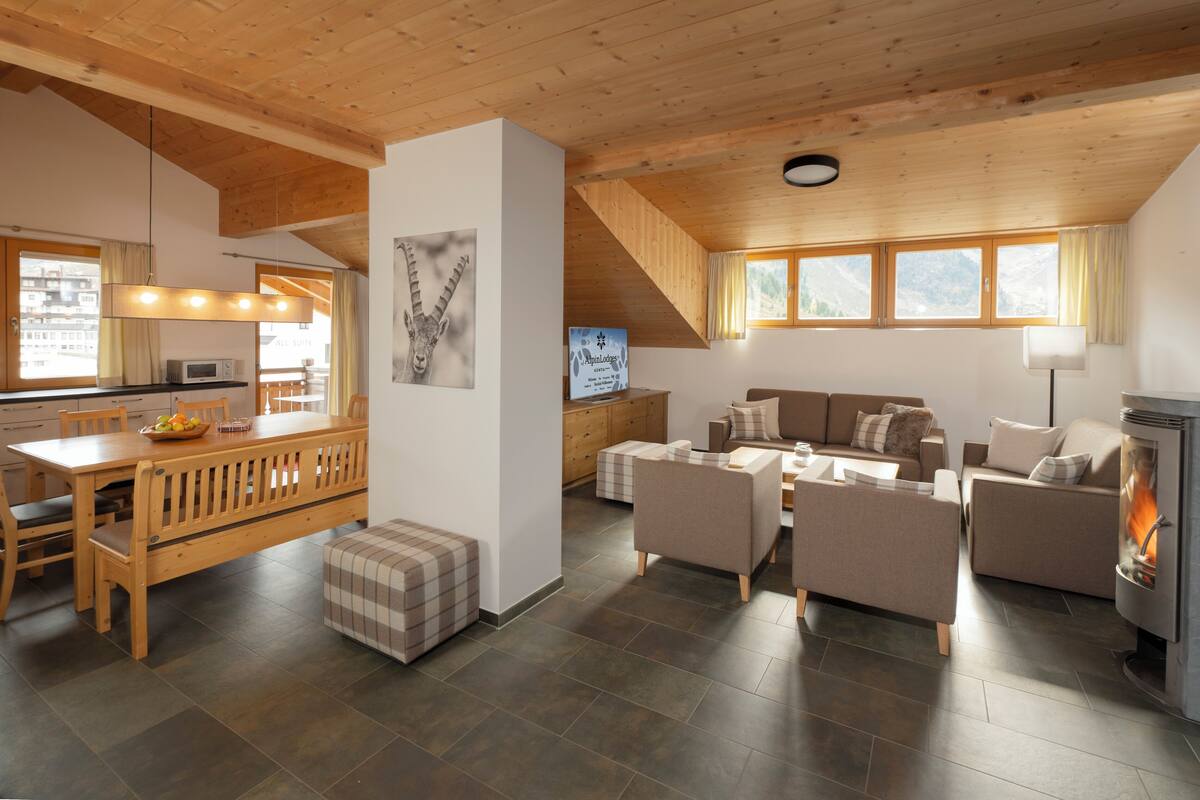Amplia sala de estar con mesa de comedor de madera, sofás y chimenea.