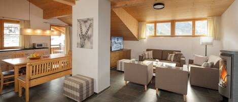 Amplia sala de estar con mesa de comedor de madera, sofás y chimenea.
