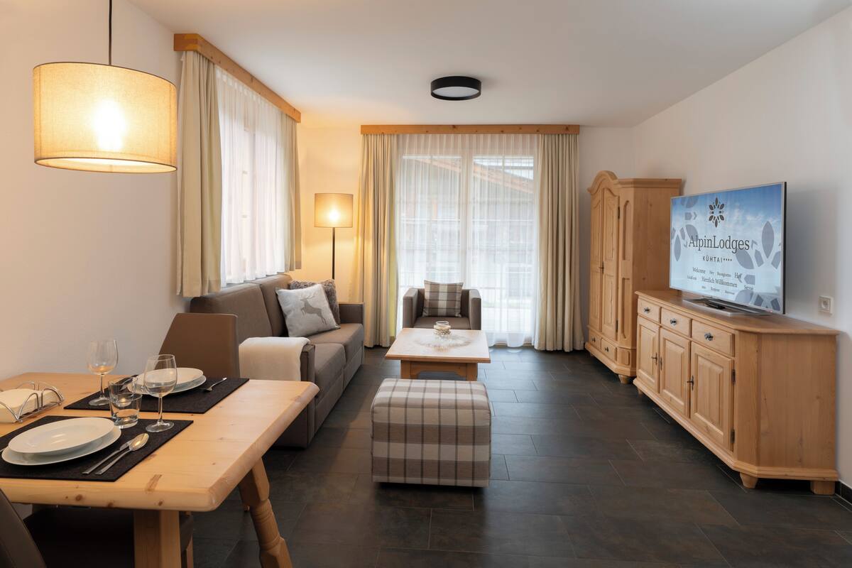 Una sala de estar moderna con comedor, un sofá, un televisor y un aparador de madera.