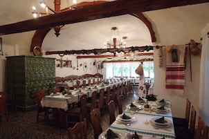 A long dining table set with multiple chairs, a green cabinet, and a chandelier.