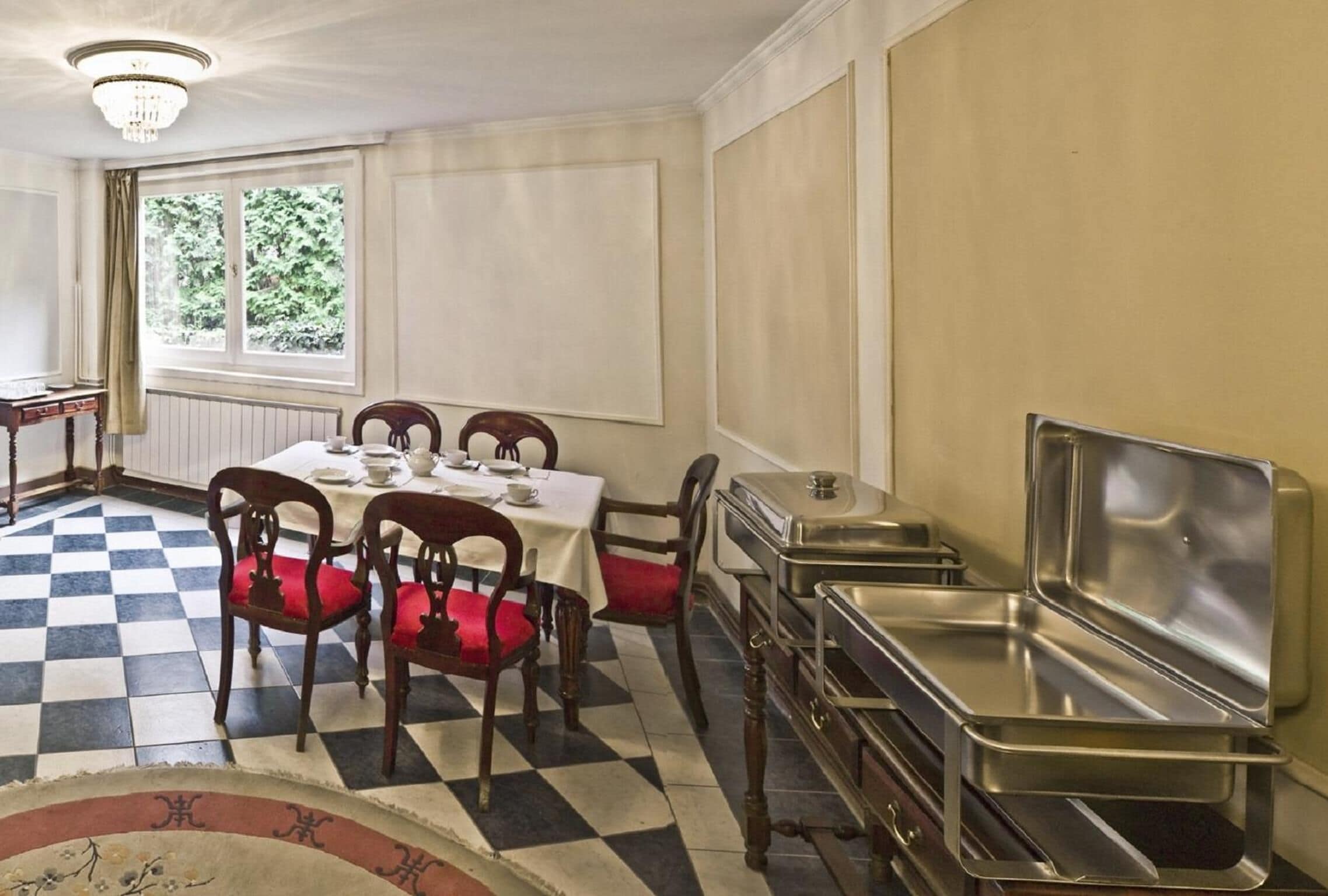 A dining area with a checkered floor, a table set for four, and a buffet station.