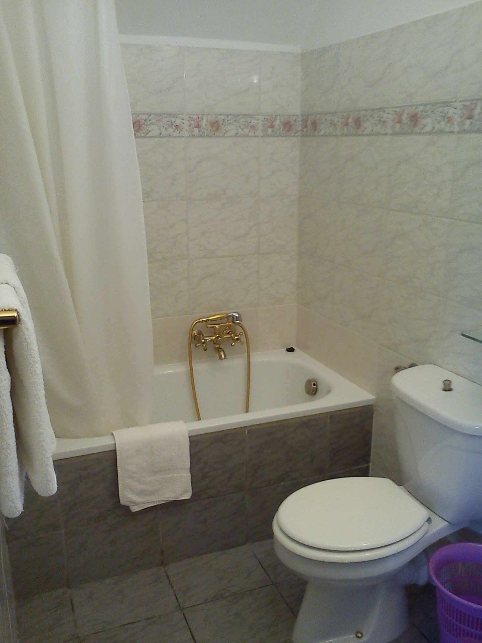 Un baño con bañera, inodoro y cortina de ducha.