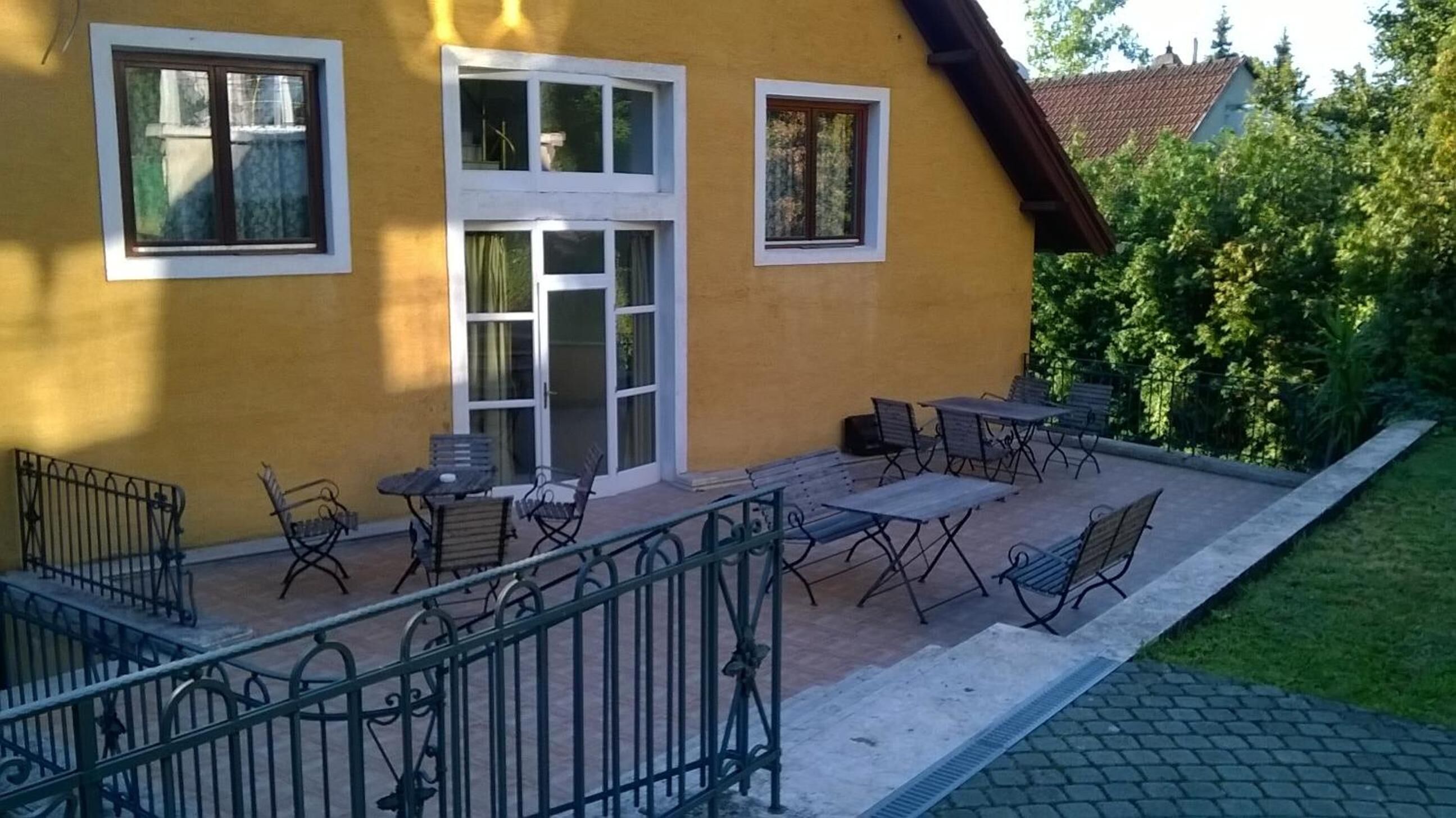 A yellow building with a patio area featuring outdoor furniture and a metal railing.