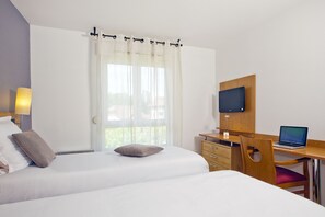 A hotel room with two beds, a desk with a laptop, a TV, and a window with curtains. - Sejours & Affaires Annecy Pont Neuf (Annecy)
