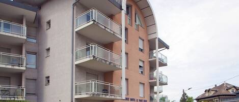 Un hôtel à plusieurs étages doté de balcons, une enseigne indiquant la présence d’une salle de sport, et un ciel dégagé.