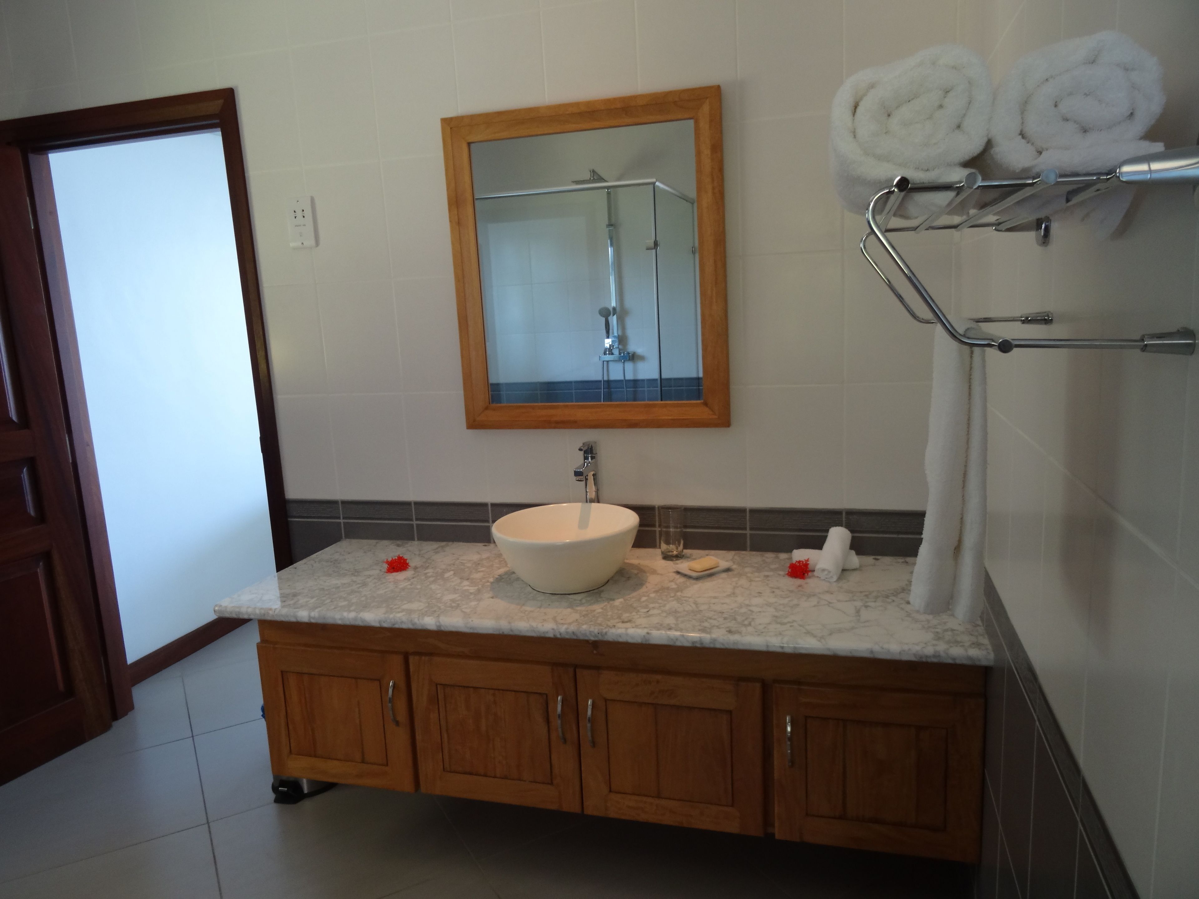 Un bagno con un mobile vanitario in legno, un lavandino bianco, uno specchio e un portascopino con asciugamani.