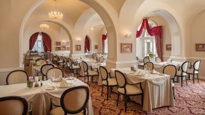 Un comedor formal con varias mesas y sillas, techos abovedados y candelabros.