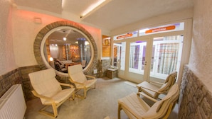 Una habitación con cuatro sillas de madera dispuestas alrededor de un espacio central, una pared de piedra y un espejo.