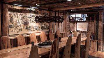 Een houten eettafel met stoelen, een kaart aan de muur en een rustiek interieur.