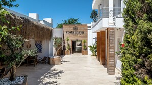 A hotel entrance with a wooden facade, potted plants, and a thatched roof structure. - Costa Maya Hotel (Bodrum)