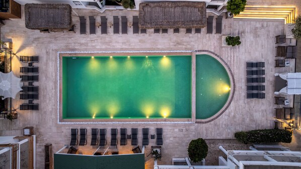 A rooftop pool with a sunken area, surrounded by lounge chairs and umbrellas.