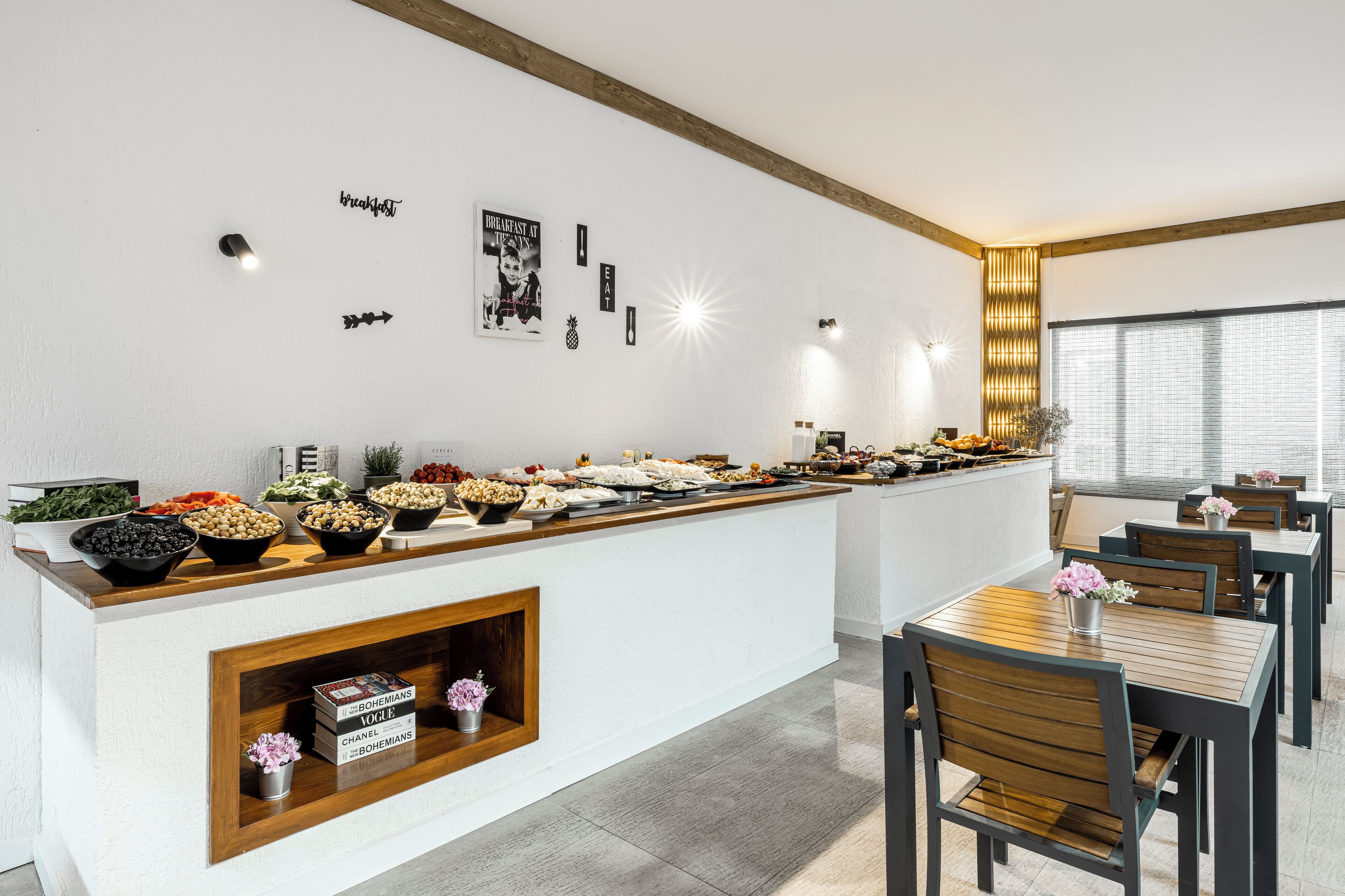 A buffet setup with various food items, a wooden counter, and a seating area with tables and chairs.