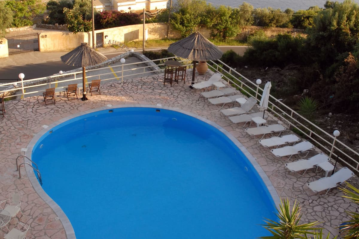 A swimming pool with lounge chairs and a view of the sea.