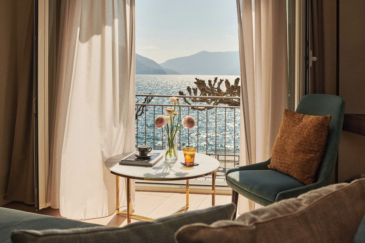 Un balcón con vistas al mar, una mesa con un florero y una silla con cojín.