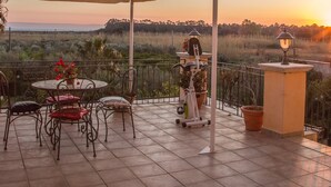 Una terraza con una mesa, sillas, una lámpara y plantas en macetas.