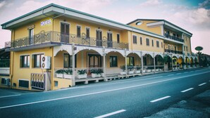 Un hotel amarillo con balcón, varias ventanas y un letrero que dice "HOTEL".
