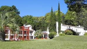 Um edifício branco com pérgola vermelha e uma palmeira em primeiro plano.