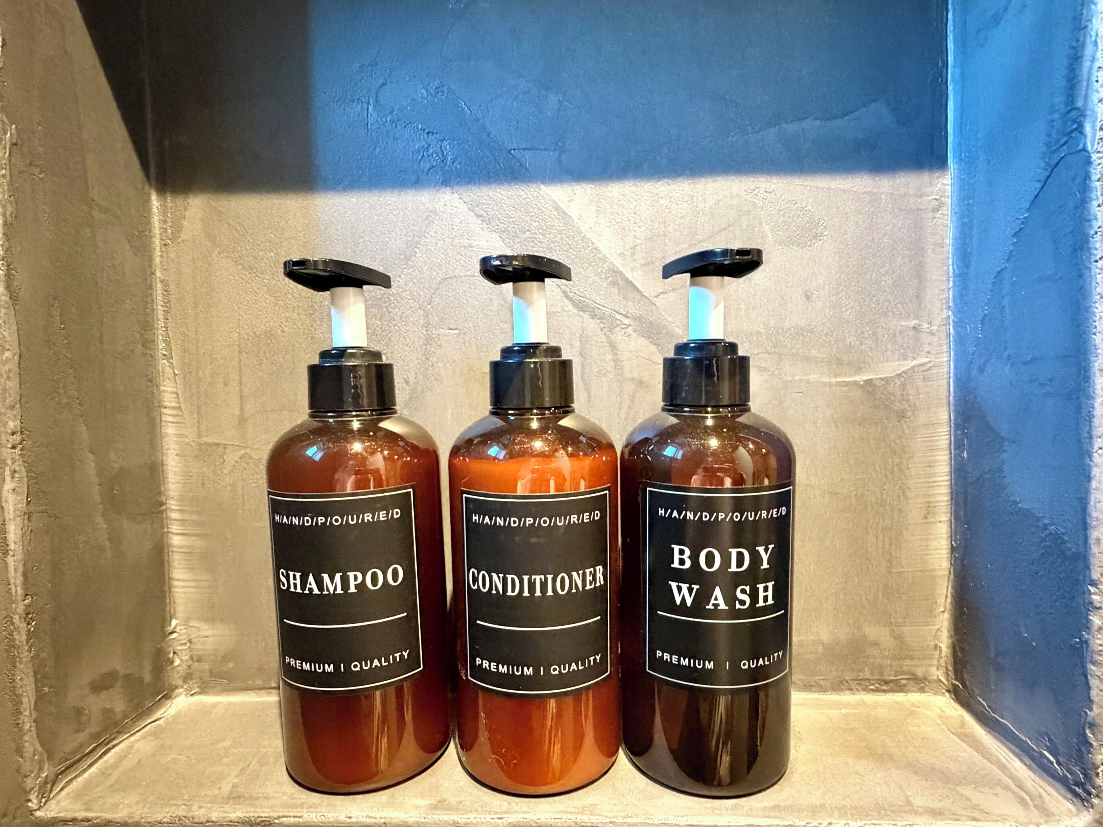 Three bottles of body wash, shampoo, and conditioner on a shelf.