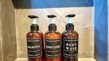 Three bottles of body wash, shampoo, and conditioner on a shelf.