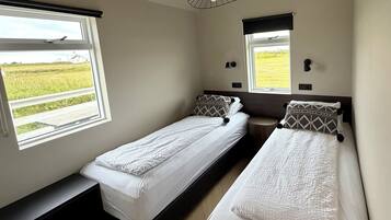A room with two single beds, a bench, and a window with a view of a field.