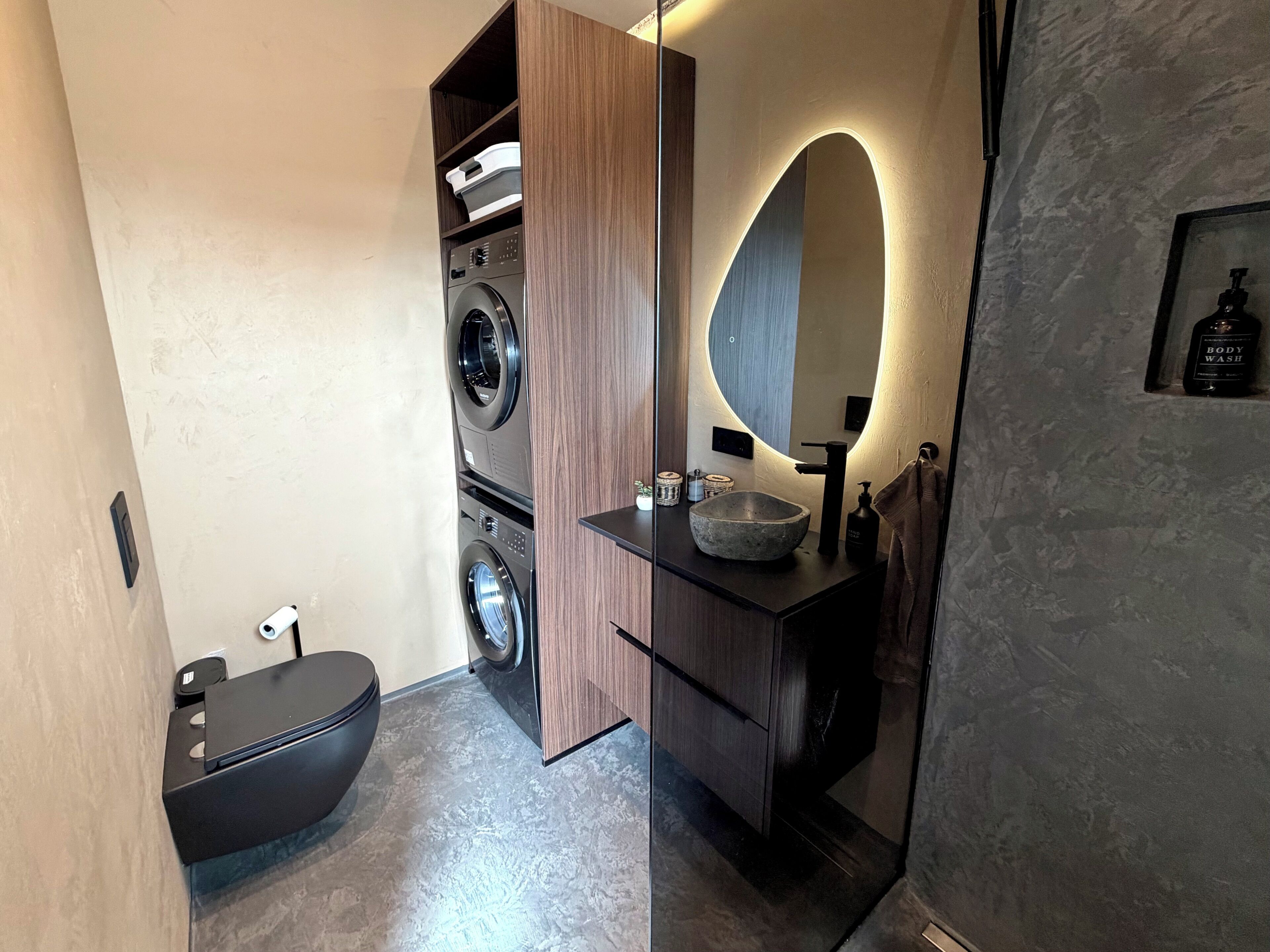 A modern bathroom with a built-in washing machine, a large mirror, and a vessel sink.