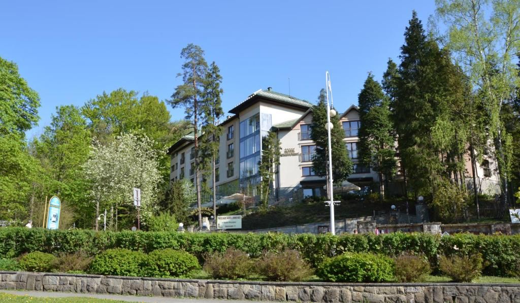 A multi-story residential building with balconies, surrounded by greenery and trees.