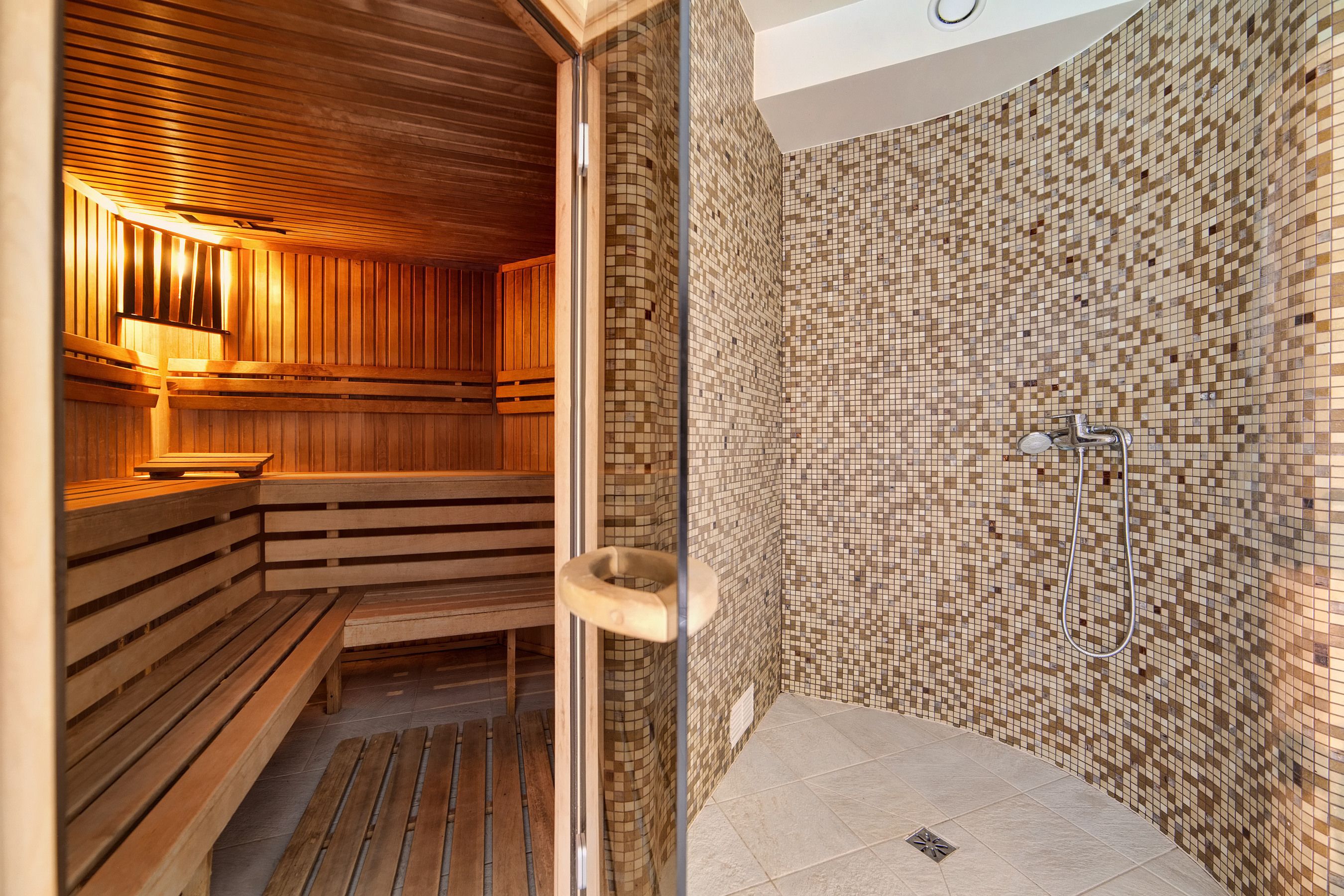 A sauna with wooden benches and a tiled wall.