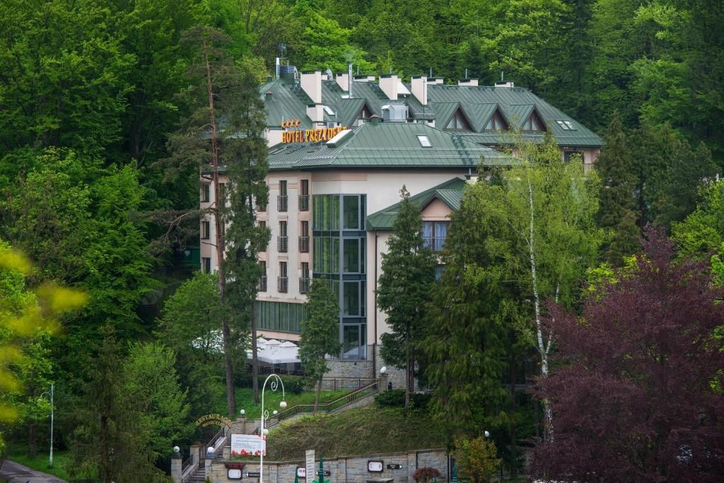 A hotel with a green roof, surrounded by trees.
