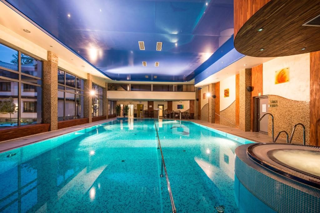 Una piscina interior amb un banyera d'hidromassatge, parets de fusta i vistes cap a l'exterior.