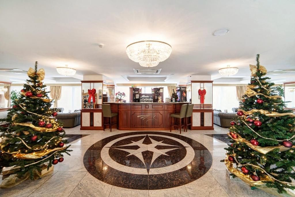 A lobby with a central bar area, two Christmas trees, and a star-shaped floor design.