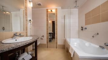 A modern bathroom with a sink, vanity, mirror, and bathtub.