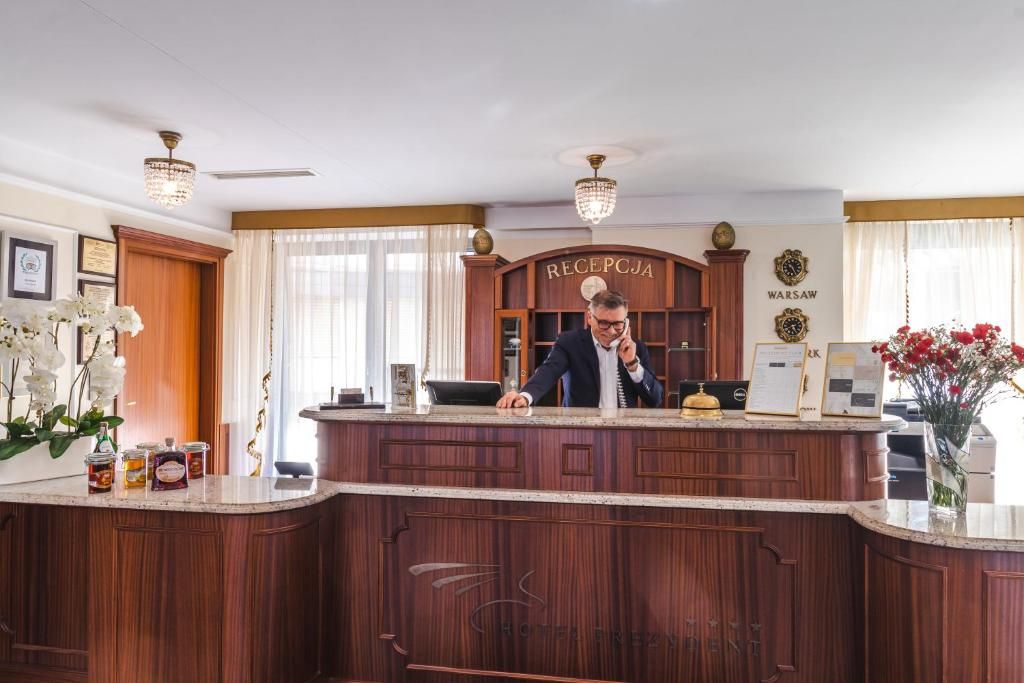 A reception desk with a wooden finish, a clock, and a sign that reads 'RECEPCJA'.