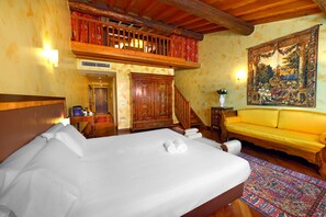 Habitación de hotel con cama, sofá, escalera de madera, un tapiz grande y techo de madera.