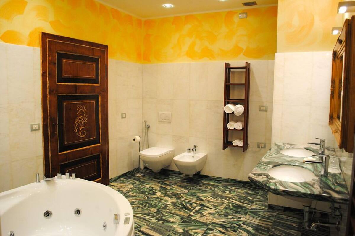 A bathroom with a large bathtub, two bidets, a vanity with two sinks, and a towel rack.