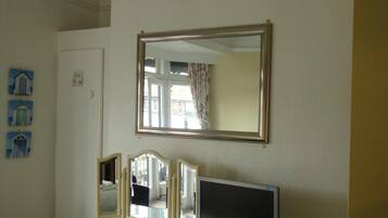 A room with a large mirror, a flat-screen TV, and a dresser.