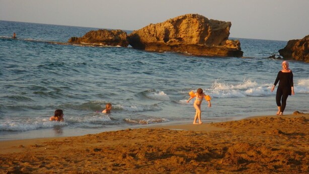 Une plage avec des formations rocheuses et des eaux calmes.